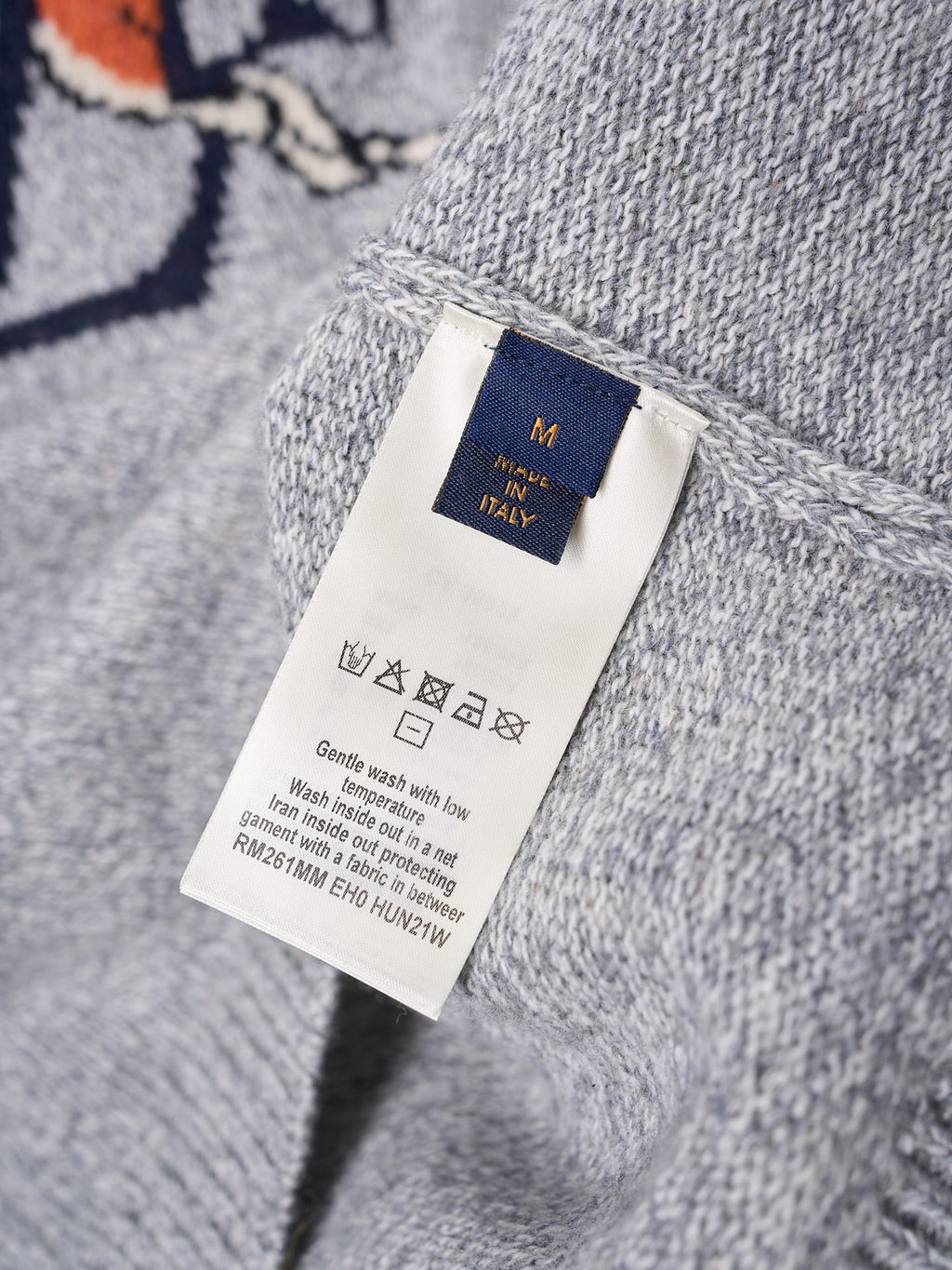 Light gray knit sweater size care tag with “M” and “Italy” on label