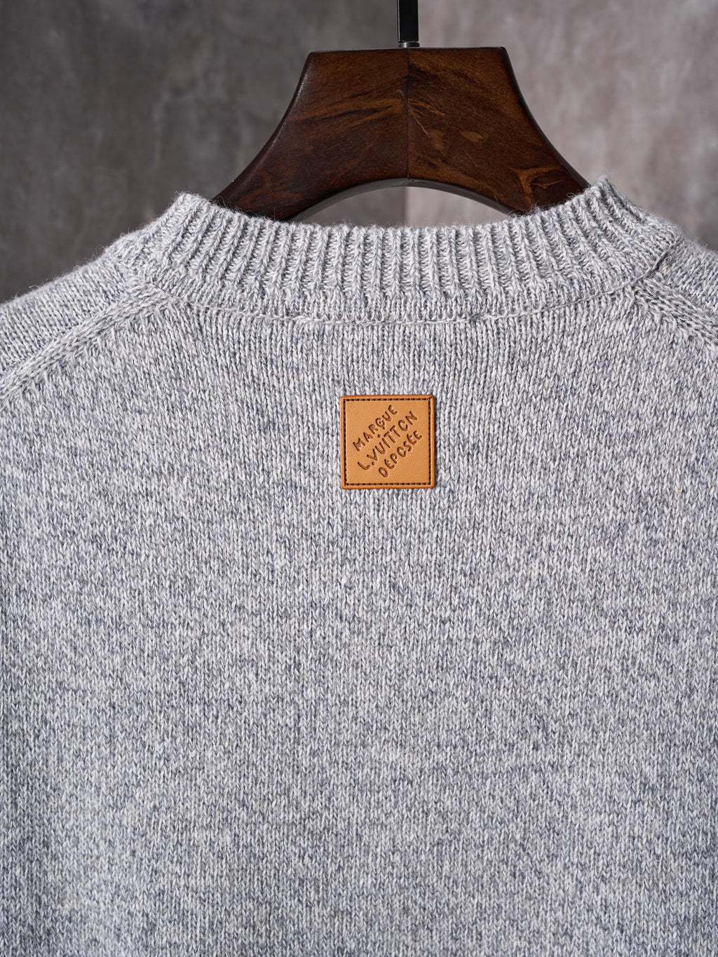 Light gray knit sweater with crew neck; small square logo label at back neckline