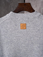 Light gray knit sweater with crew neck; small square logo label at back neckline