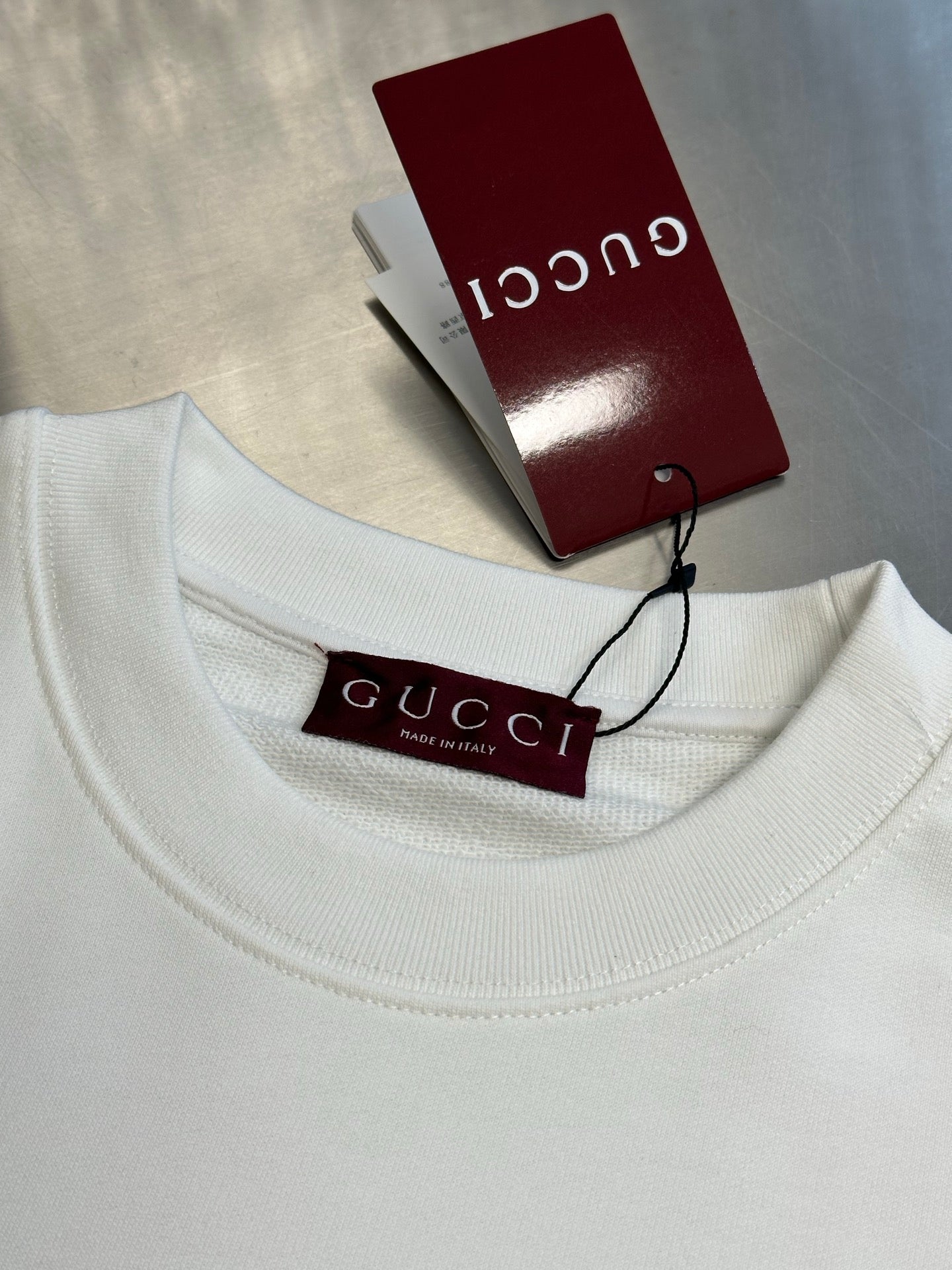 White Gucci sweatshirt neckline with Gucci tag and size label