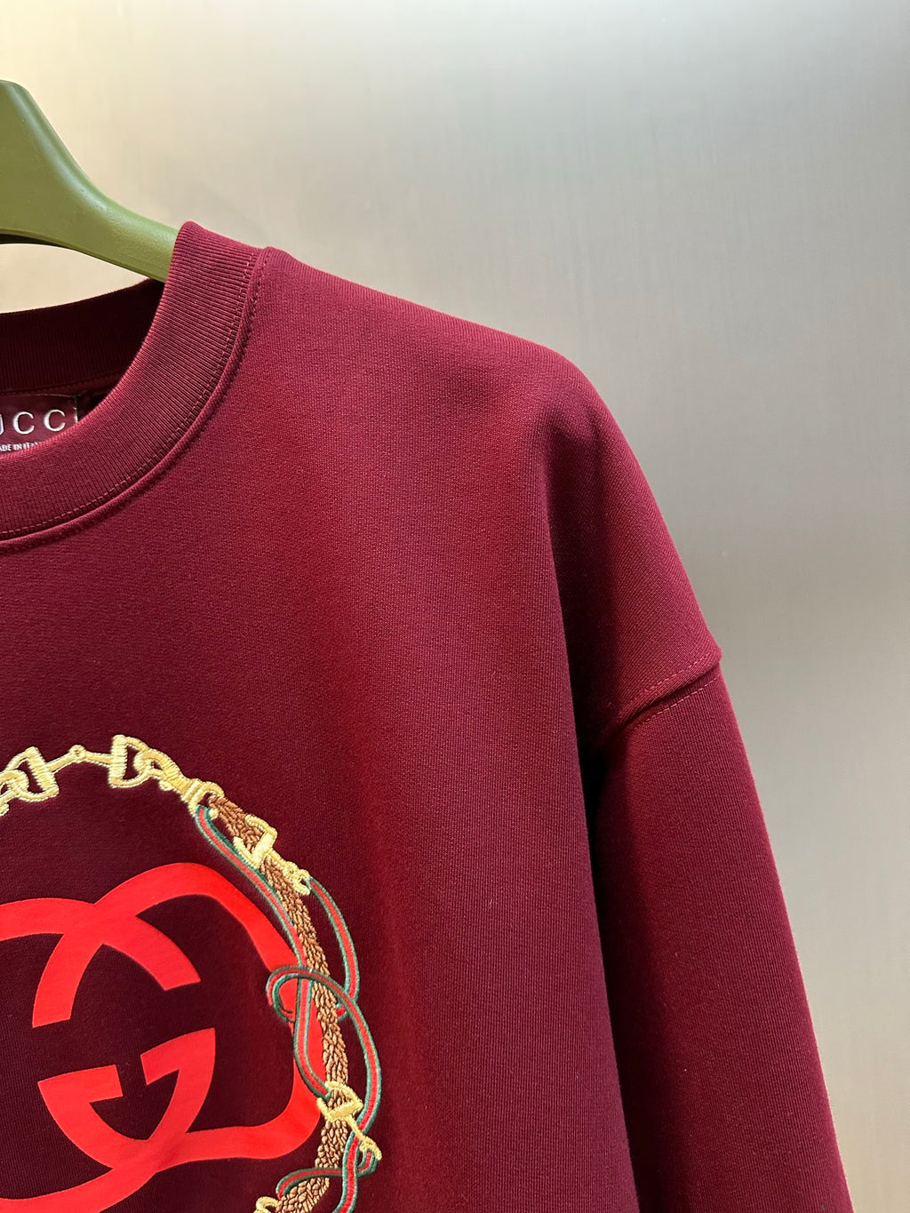 Maroon sweatshirt with large red GG logo print and gold chain trim detail