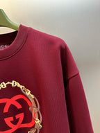 Maroon sweatshirt with large red GG logo print and gold chain trim detail