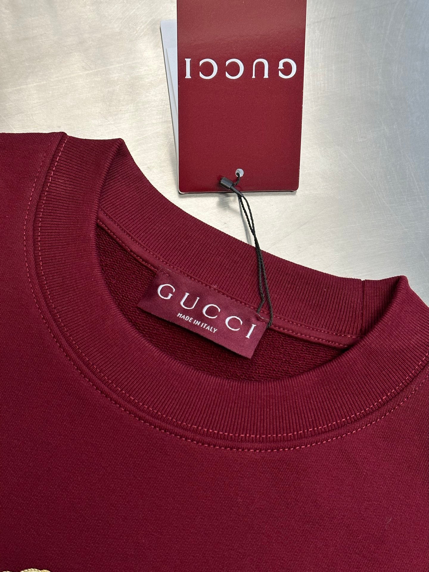 Maroon crewneck sweatshirt with ribbed neckline and Gucci label at collar
