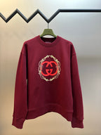 Maroon crewneck sweatshirt with red GG logo and gold chain trim on chest