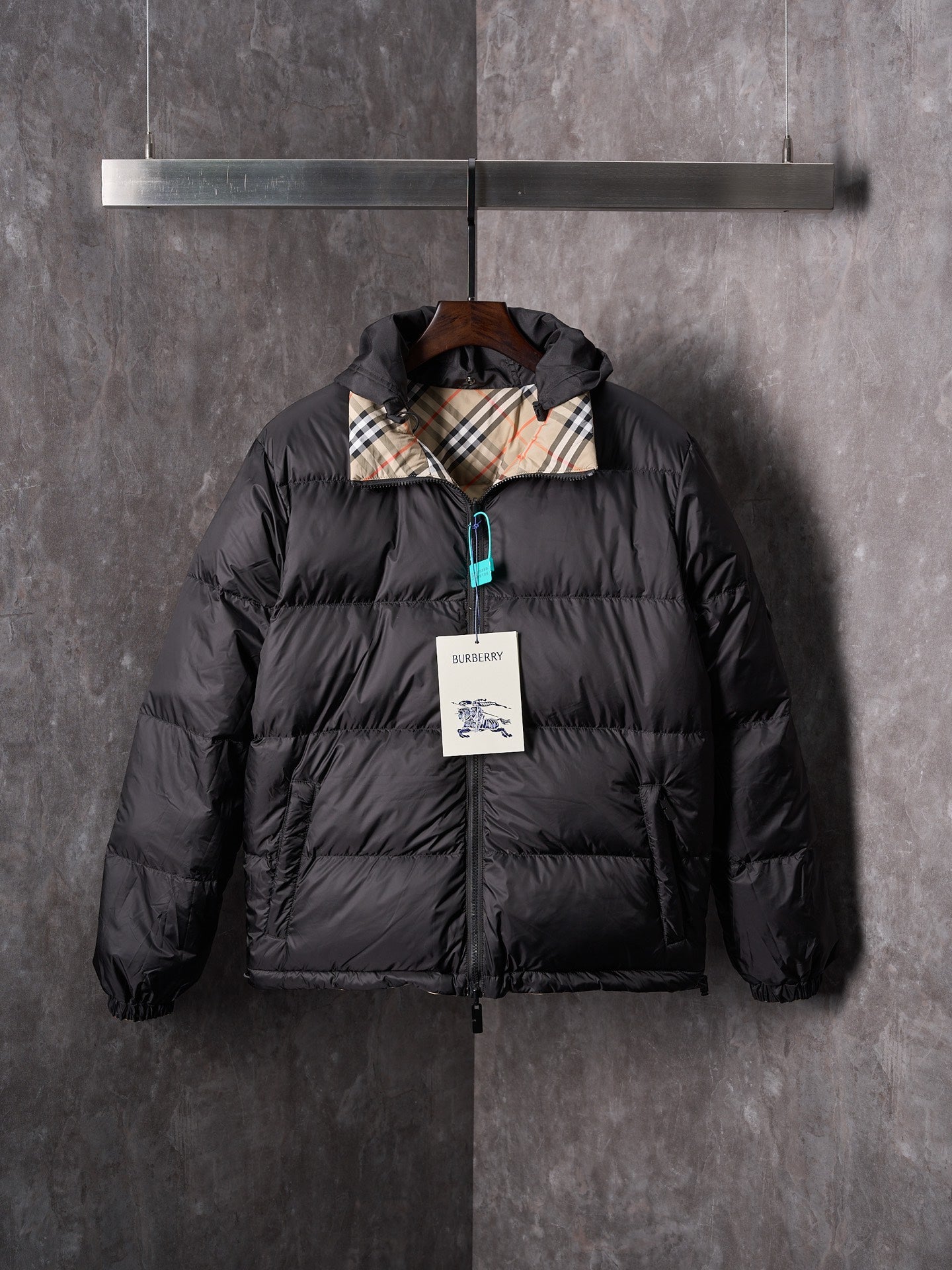 Black puffer jacket with attached hood and full front zip, teal zipper pull detail.