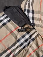 Plaid puffer jacket close-up with black hood cuff and gathered fabric trim.