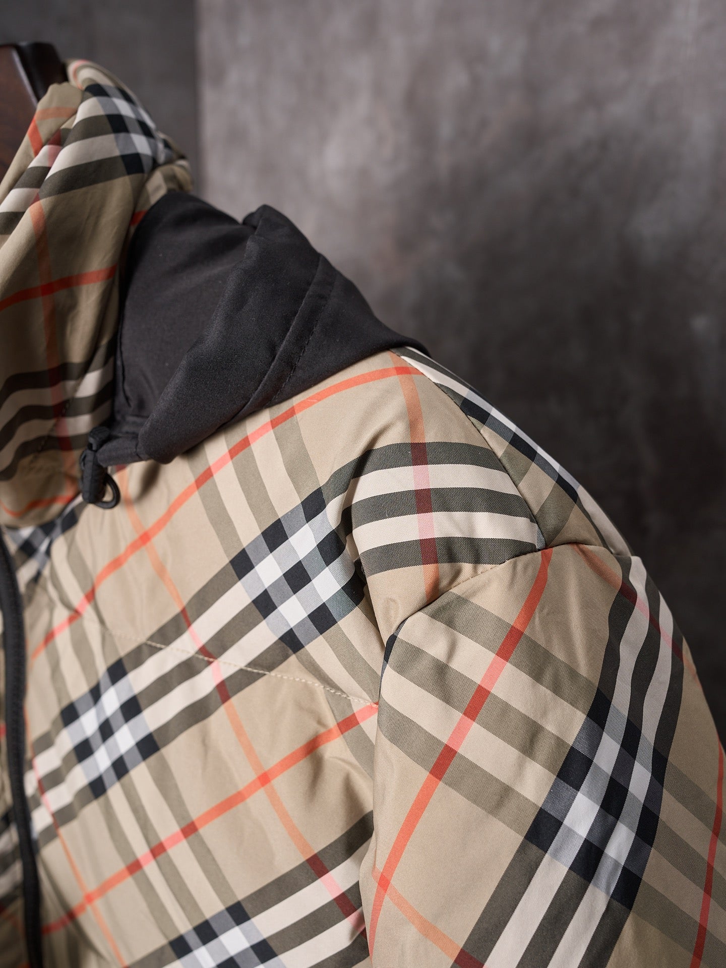 Plaid puffer jacket side view with black hood edge and padded sleeve panel.