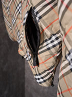 Plaid puffer jacket side close-up with black zipper and inner dark lining edge.