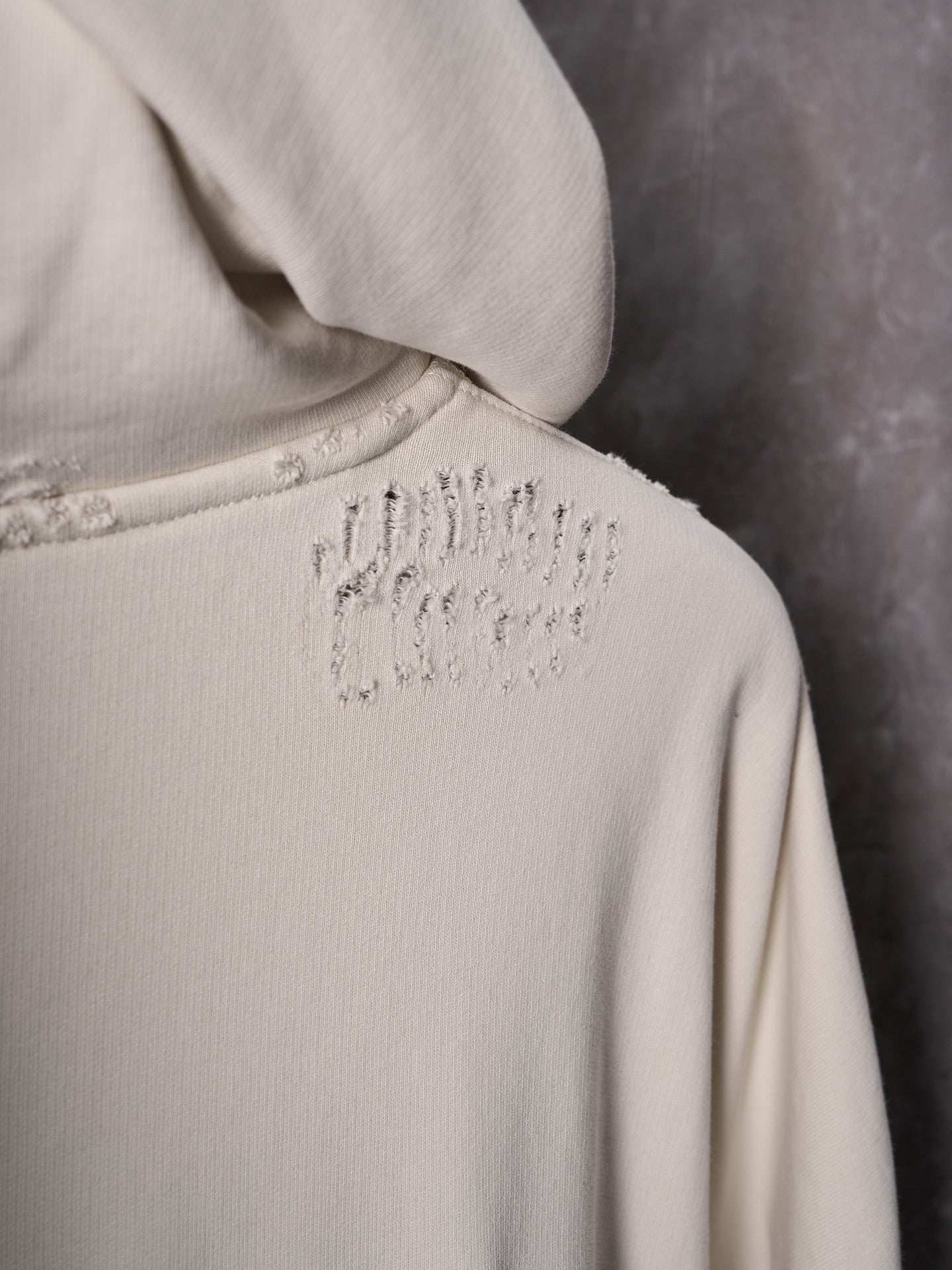 Off-white hoodie back with small studded logo near hood seam