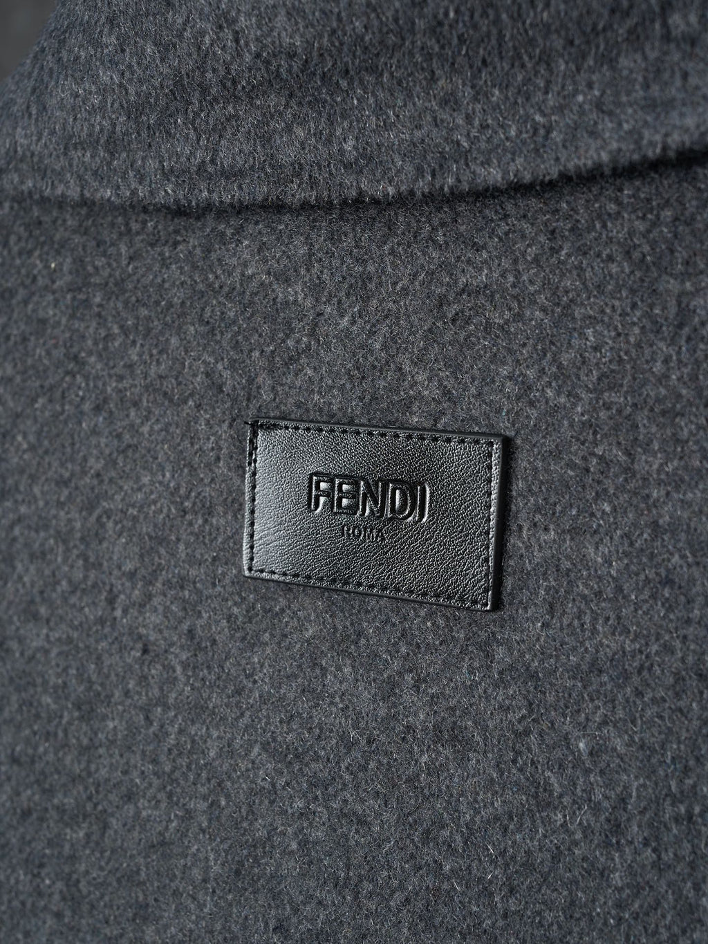 Long dark Fendi garment with FENDI logo label at chest