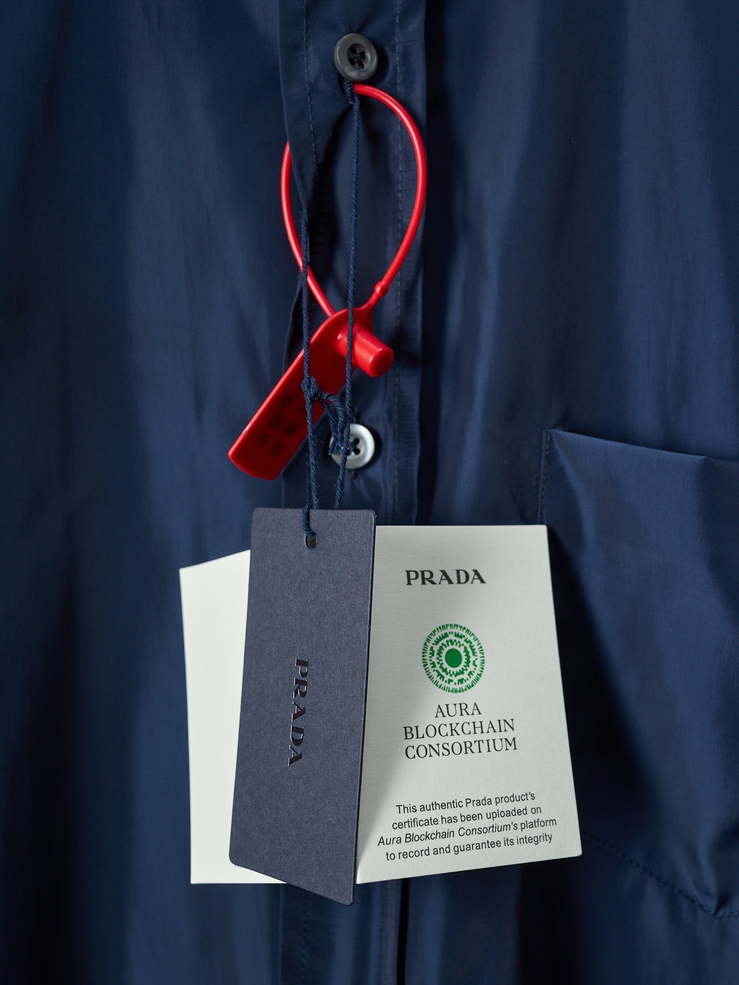 Navy Prada shirt front close-up with black button and red cord key tag