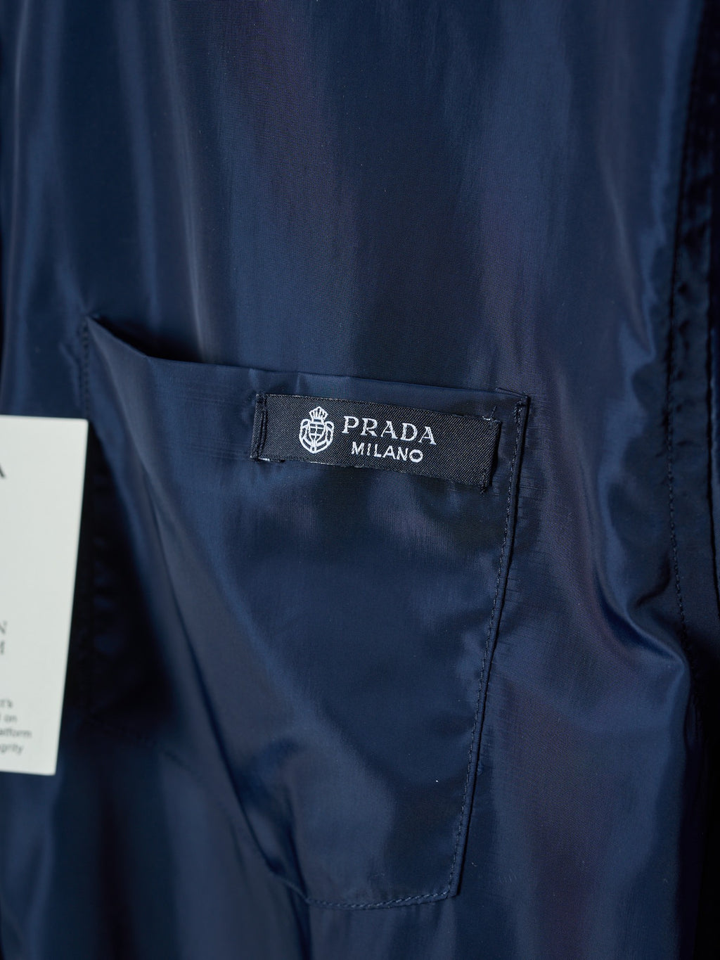 Navy Prada chest pocket with branded label, close-up on fabric texture