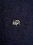 Close-up of dark navy knit sweater fabric with small textured animal emblem