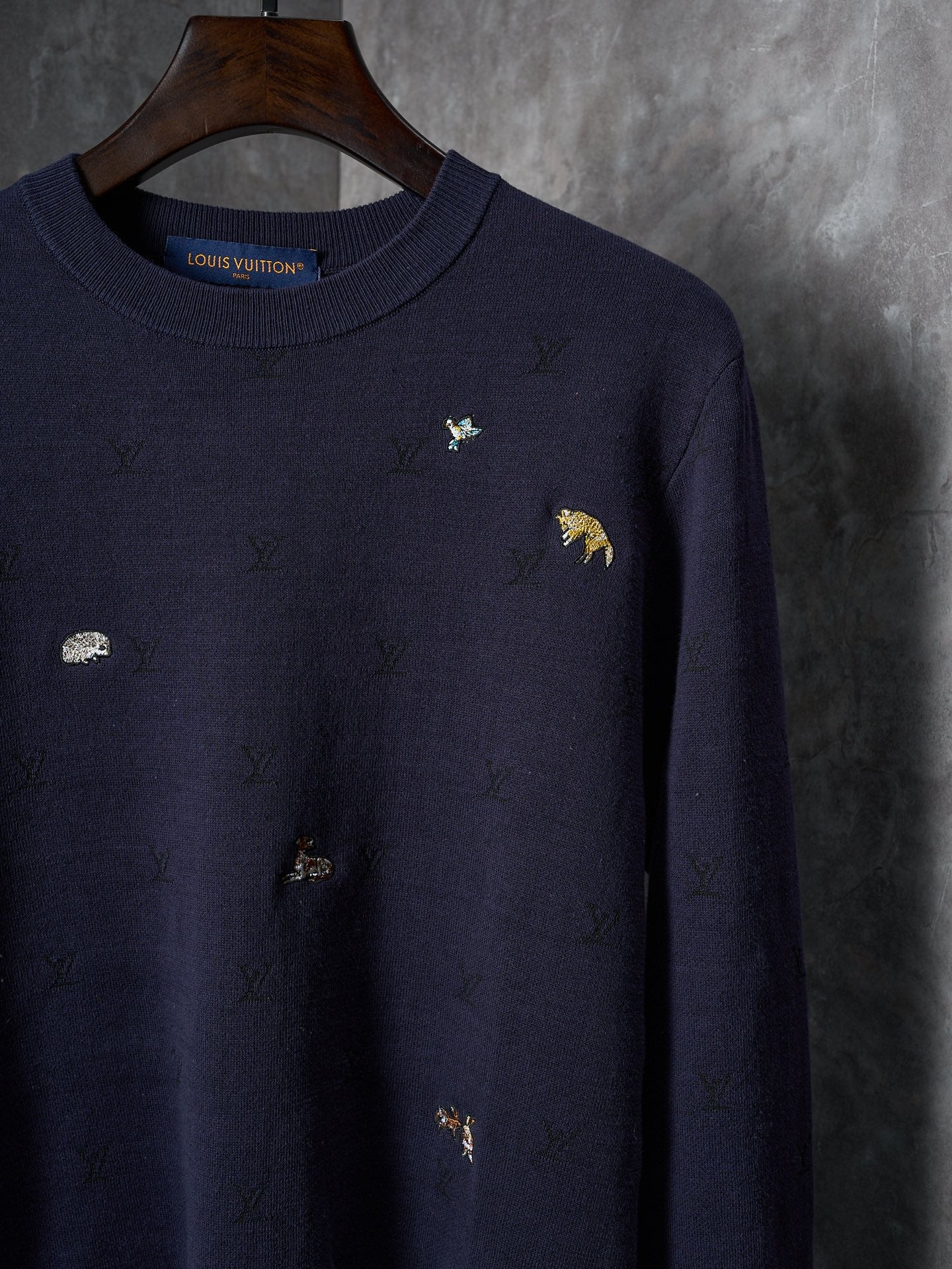 Long-sleeve knit sweater in dark navy with embroidered icons across the chest and sleeves