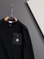 Black long-sleeve sweatshirt with crew neck, chest pocket, and logo patch