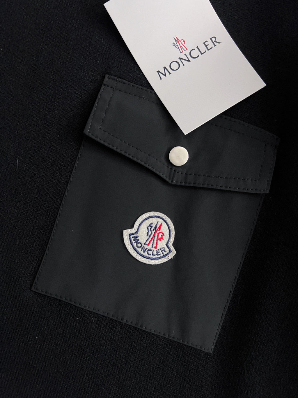 Black pocket patch detail with snap button and embroidered round logo