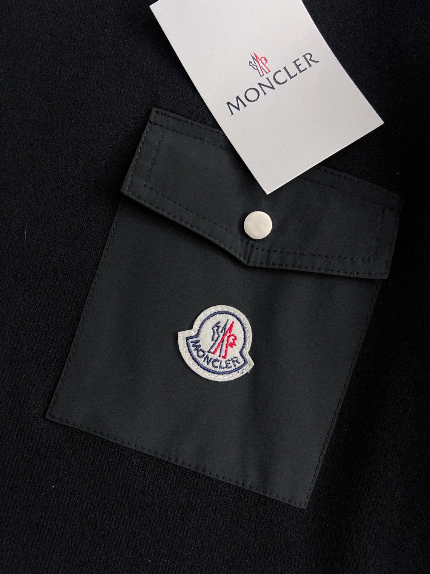 Black pocket patch detail with snap button and embroidered round logo
