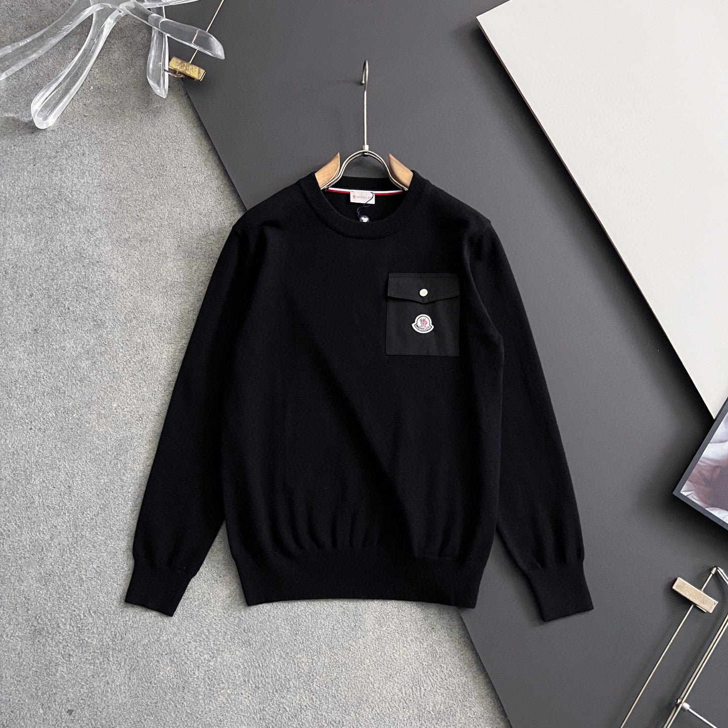 Black long-sleeve sweatshirt with front pocket and small chest badge patch
