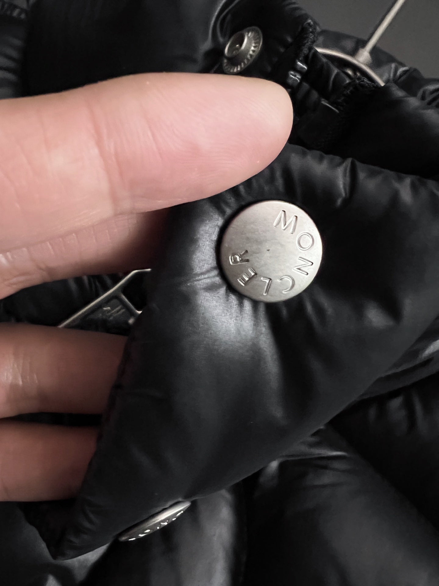 Moncler puffer jacket fabric detail with snap button and metal logo stamp