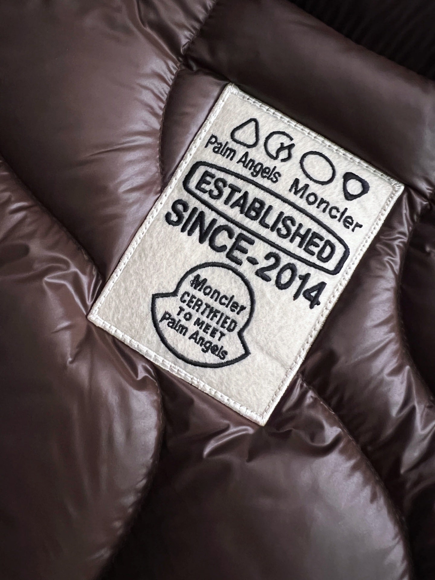 Palm Angels Moncler label reading 'ESTABLISHED 2014' on dark brown quilted fabric
