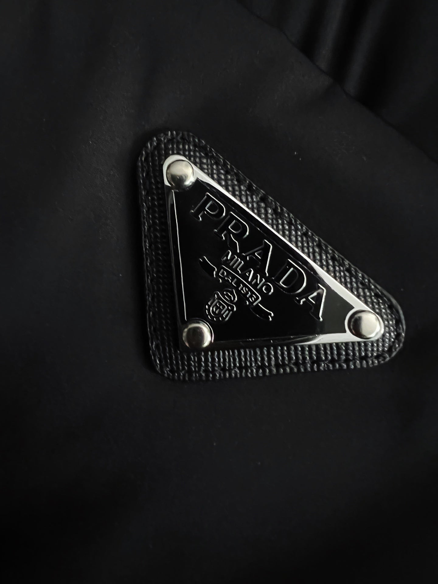 Prada triangle logo patch with textured border on black puffer fabric