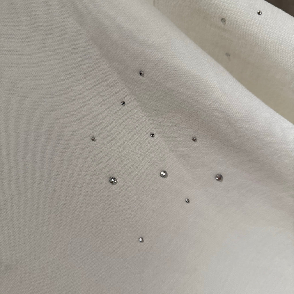 White T-shirt fabric with scattered rhinestone studs across the surface