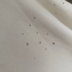 White T-shirt fabric with scattered rhinestone studs across the surface