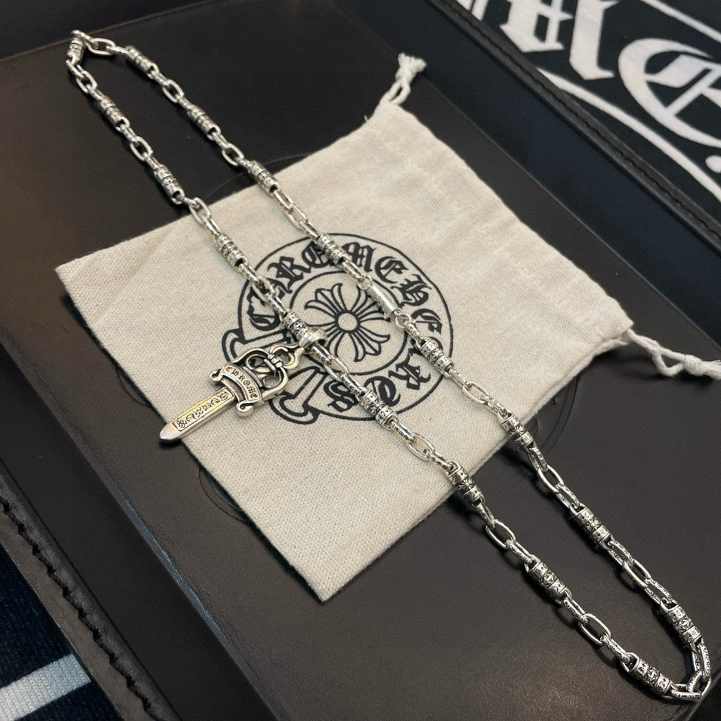 Silver-tone necklace with dagger pendant on fabric pouch