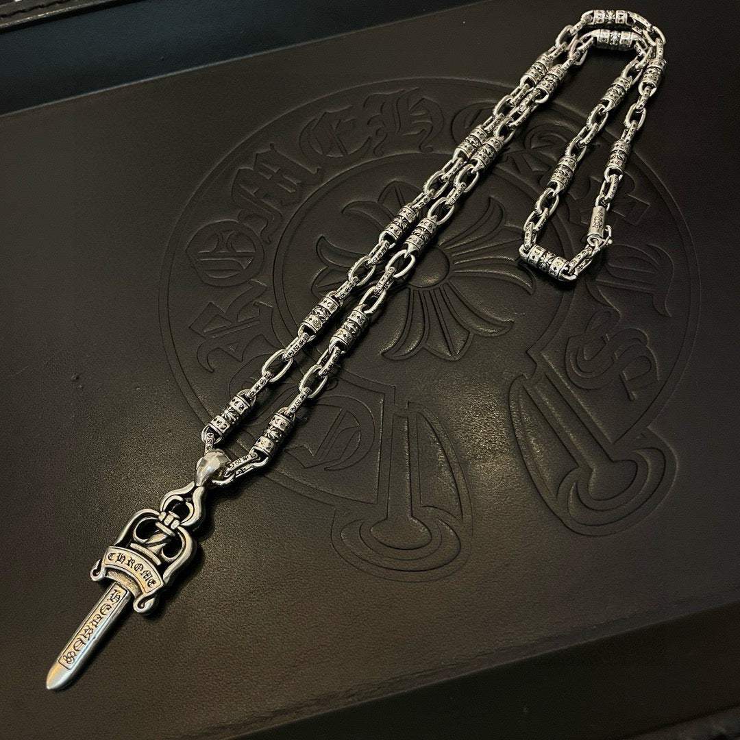 Silver-tone necklace with dagger charm pendant on embossed surface