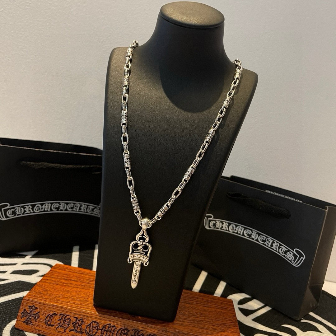 Silver-tone double-chain necklace with dagger pendant on display stand