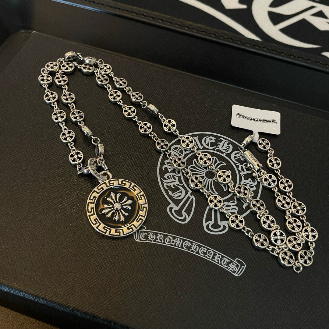 Silver chain necklace with round medallion pendant and rectangular tag on tray