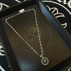 Silver chain necklace with round flower medallion pendant, laid on gift tray