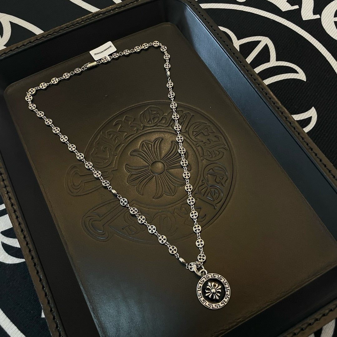 Silver chain necklace with round flower medallion pendant, laid on gift tray