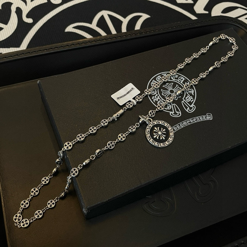 Silver chain necklace with round pendant and scroll bar charm on jewelry box