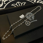Silver chain necklace with round pendant and scroll bar charm on jewelry box
