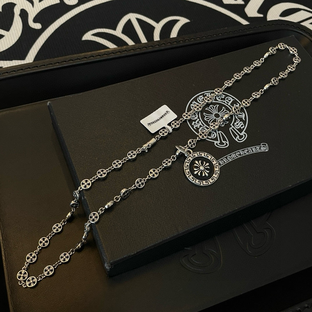 Silver chain necklace with round pendant and scroll bar charm on jewelry box