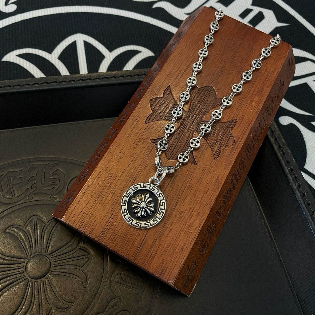 Silver chain necklace with round medallion pendant resting on wooden jewelry box