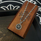 Silver chain necklace with round medallion pendant resting on wooden jewelry box