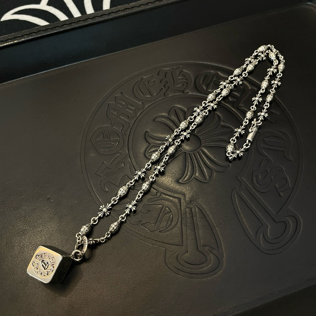Silver chain necklace with square tag pendant laid on dark leather surface
