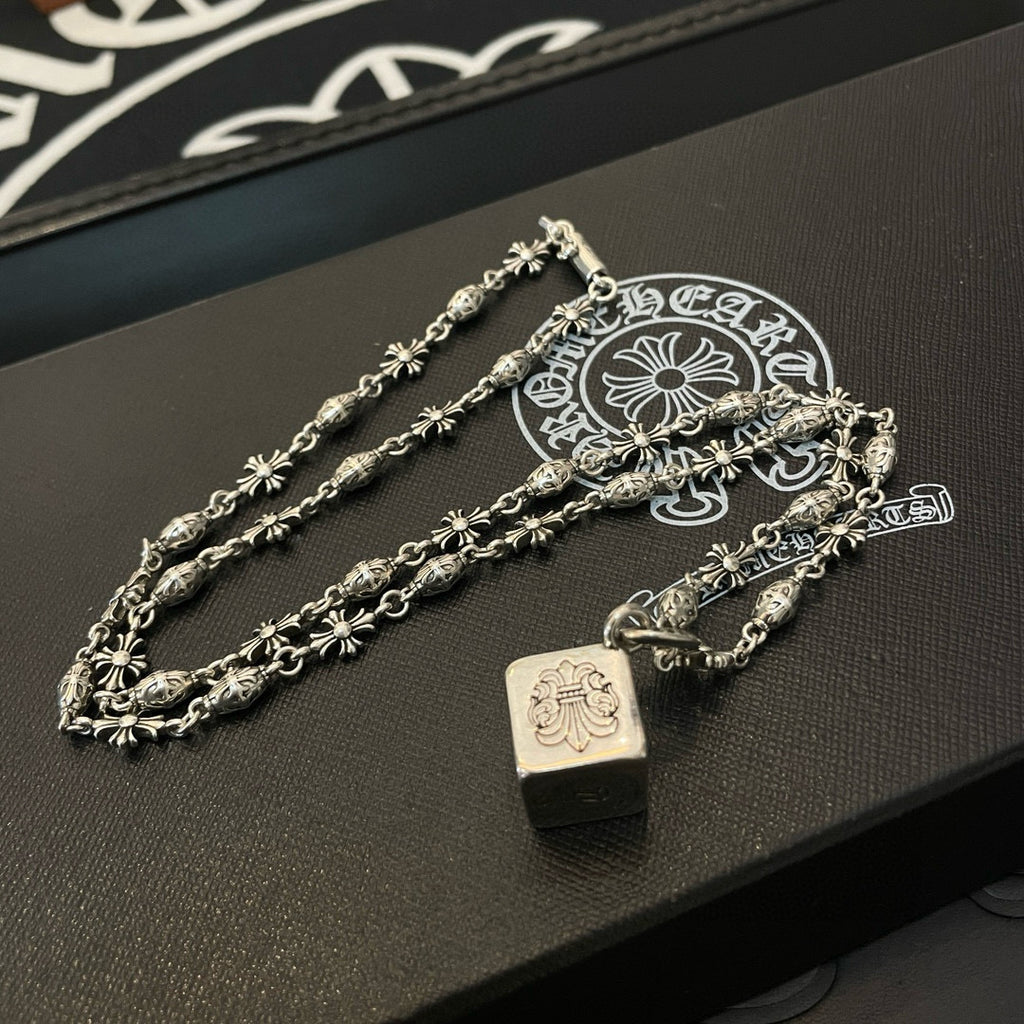 Silver chain necklace set with square pendant and floral links on display tray