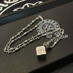 Silver chain necklace set with square pendant and floral links on display tray