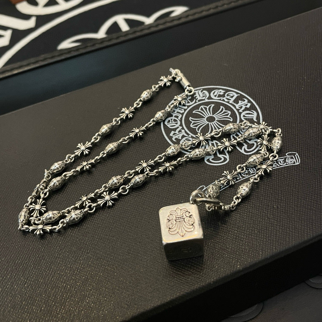Silver chain necklace set with square pendant and floral links on display tray