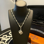 Silver chain necklace on bust display with square pendant and detailed charm accents