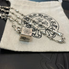 Silver chain necklace with square pendant and small flower links on fabric pouch