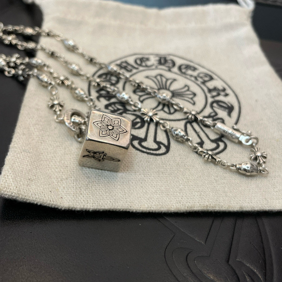 Silver chain necklace with square pendant and small flower links on fabric pouch