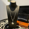 Silver chain necklace with square pendant and small charm links on bust display