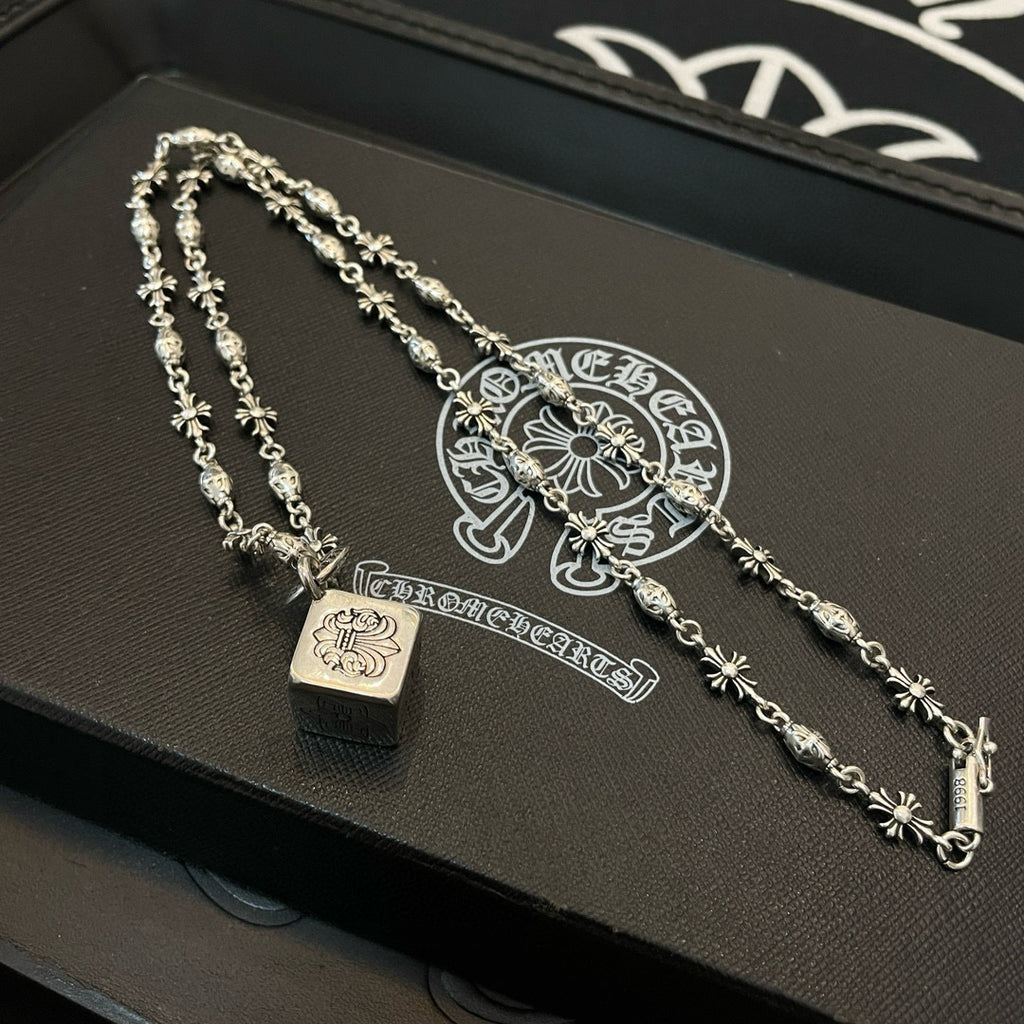 Silver chain necklace set with square pendant and floral motif links on box