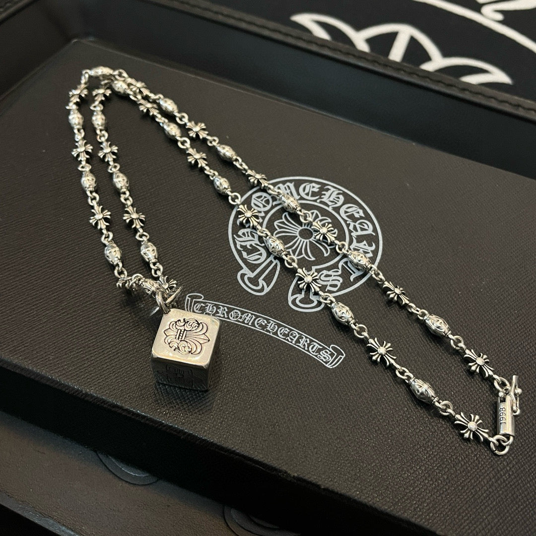 Silver chain necklace set with square pendant and floral motif links on box