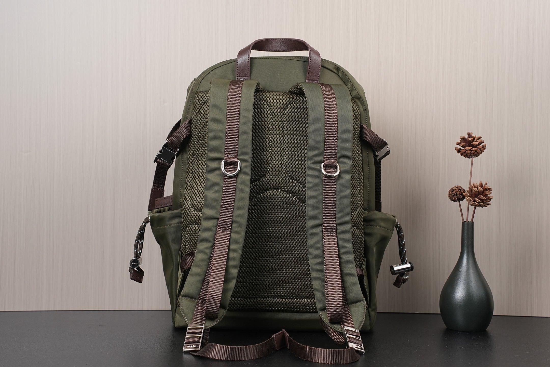 Olive green backpack with textured back panel, brown straps, and side pockets