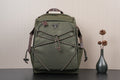 Olive green Prada-style backpack with front zipper pocket and braided trim